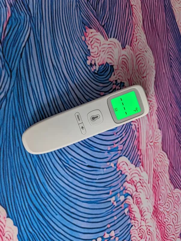 Phone photo of a no-touch thermometer on a patterned desk mat